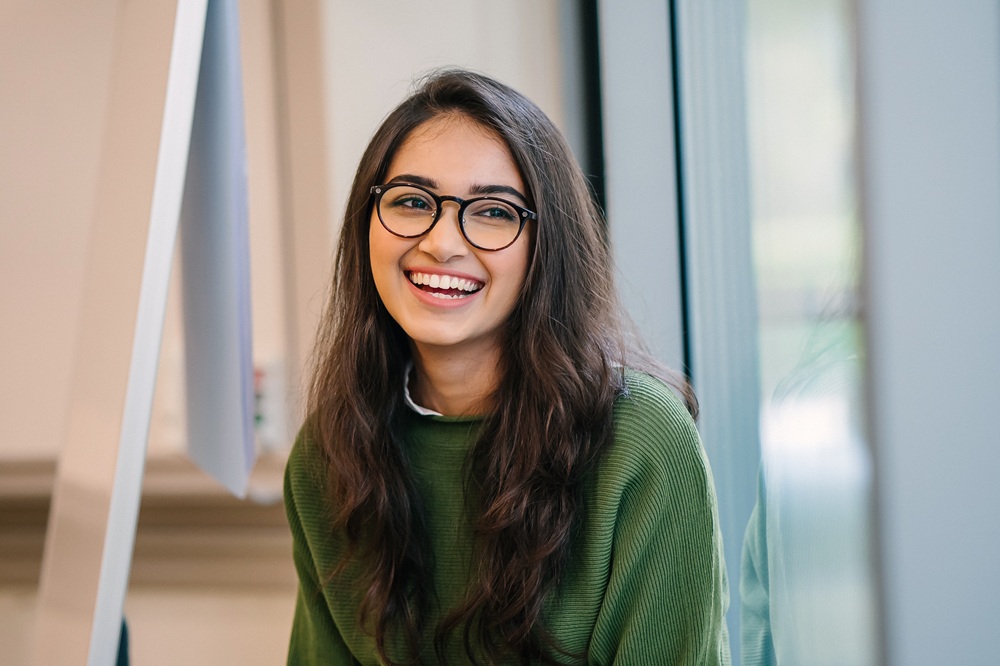 Smiling woman in glasses representing patient education on eye conditions and understanding what are nerve palsies - what are nerve palsies