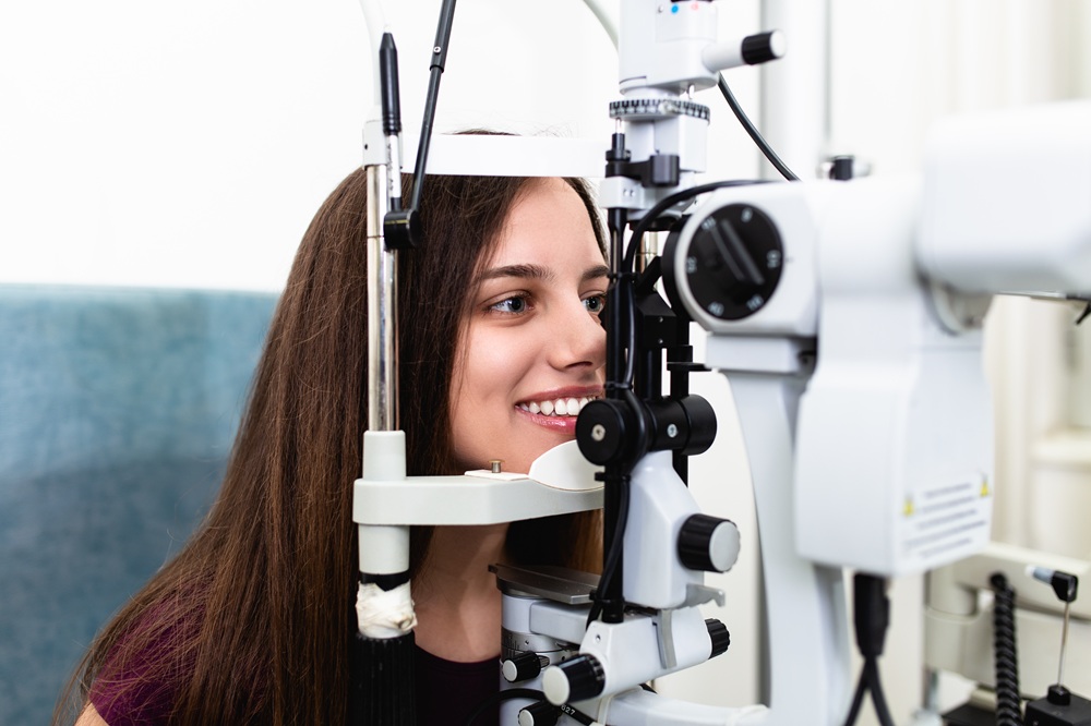 Young woman undergoing advanced retinal imaging exam - IC Retina Patient smiling while receiving detailed retina scan with modern ophthalmology equipment at IC Retina clinic - IC Retina