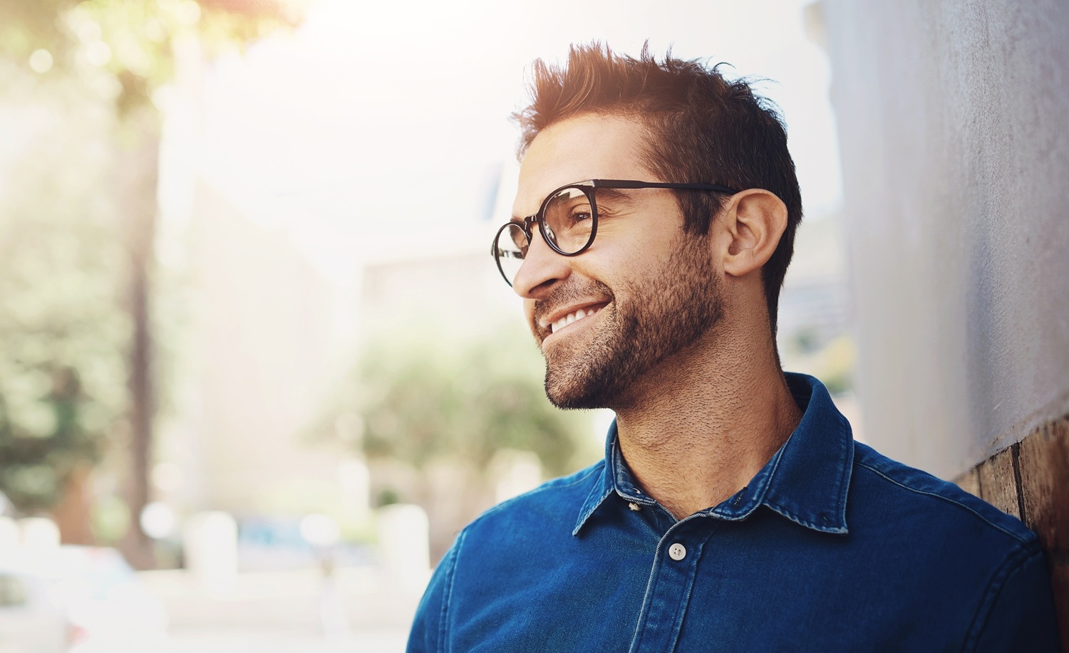 Man wearing stylish prescription glasses with clear vision - IC Laser Eye Care Smiling man outdoors wearing modern eyeglasses after vision correction and eye care treatment - IC Laser Eye Care